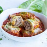 Stuffed cabbage rolls are served in a white bowl.
