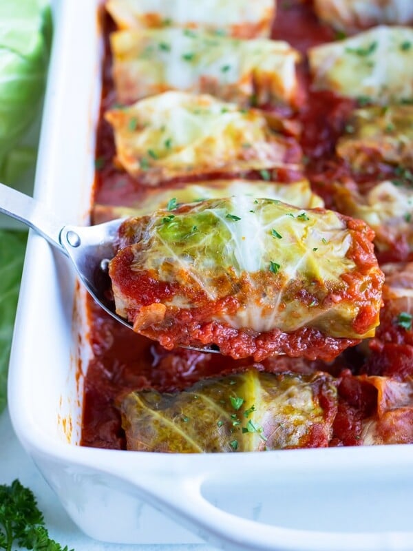 One cabbage roll is lifted out by a metal spoon.