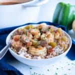 Sausage and shrimp gumbo is served with rice in a white bowl for dinner.