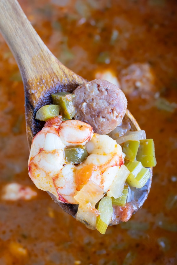 Easy shrimp and sausage gumbo is lifted up by a wooden spoon.