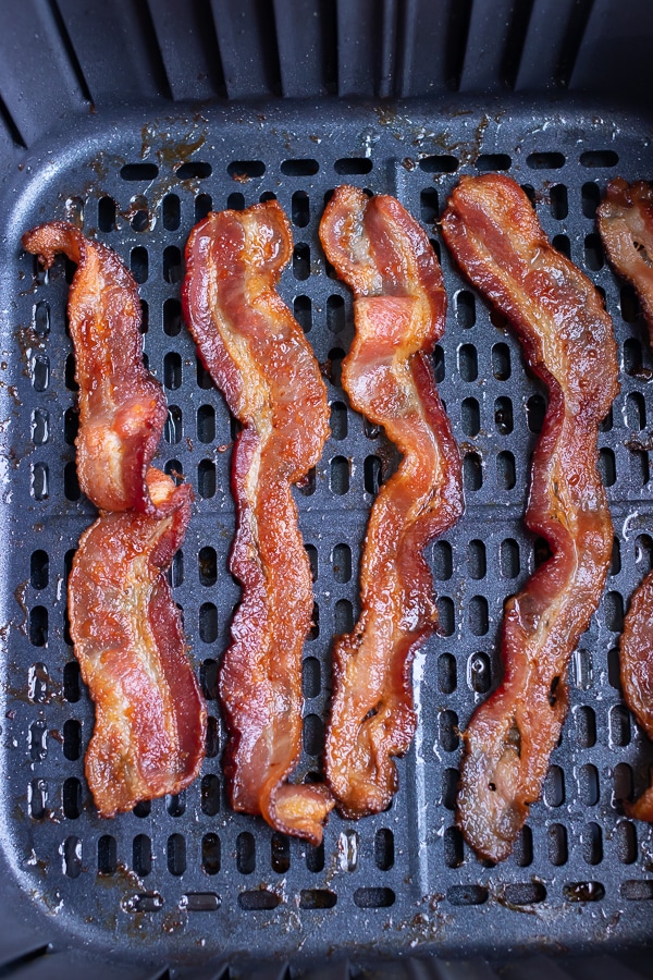 Cooked bacon is shown in one layer in the air fryer.