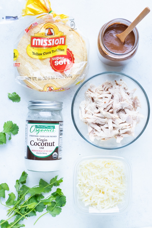 Coconut oil, chicken, corn tortillas, mole sauce, cheese, and cilantro are the ingredients for this recipe.