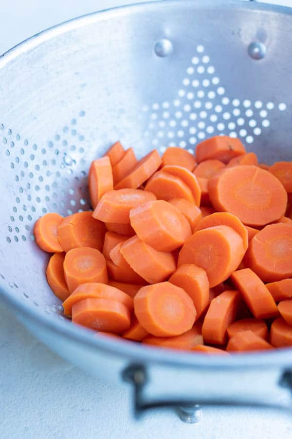 Boiled carrots are left in a strainer.