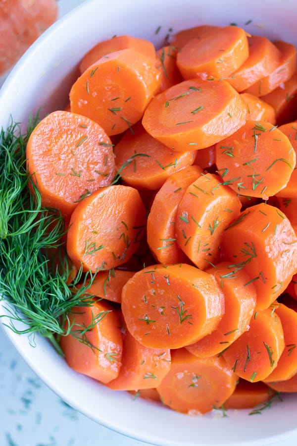 Sliced and seasoned boiled carrots are served in a white bowl.