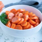 Boiled carrots are served in a white bowl.