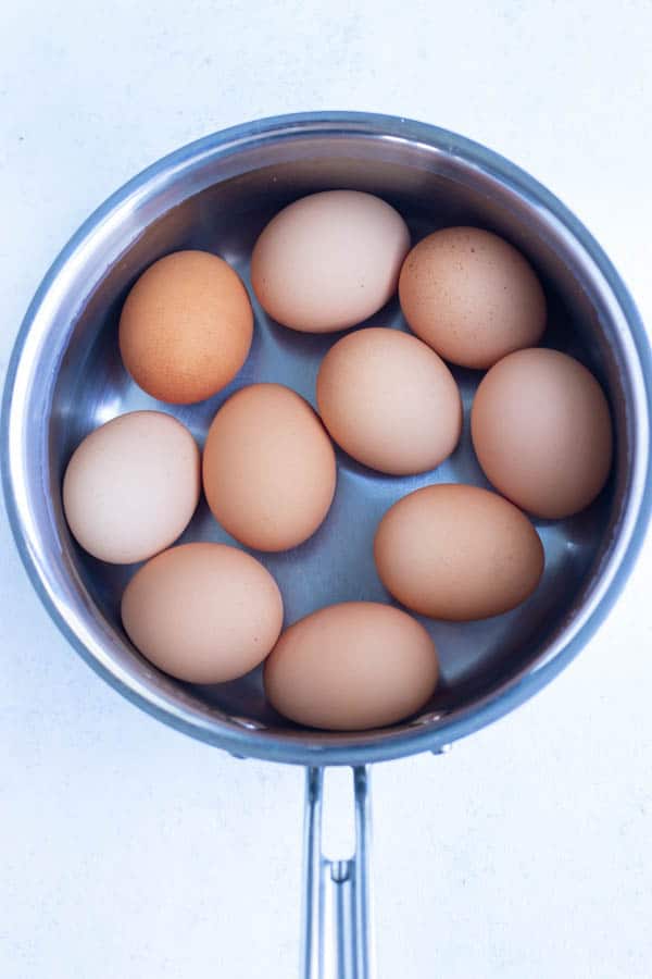 Eggs are boiled in a metal pot on the stove.