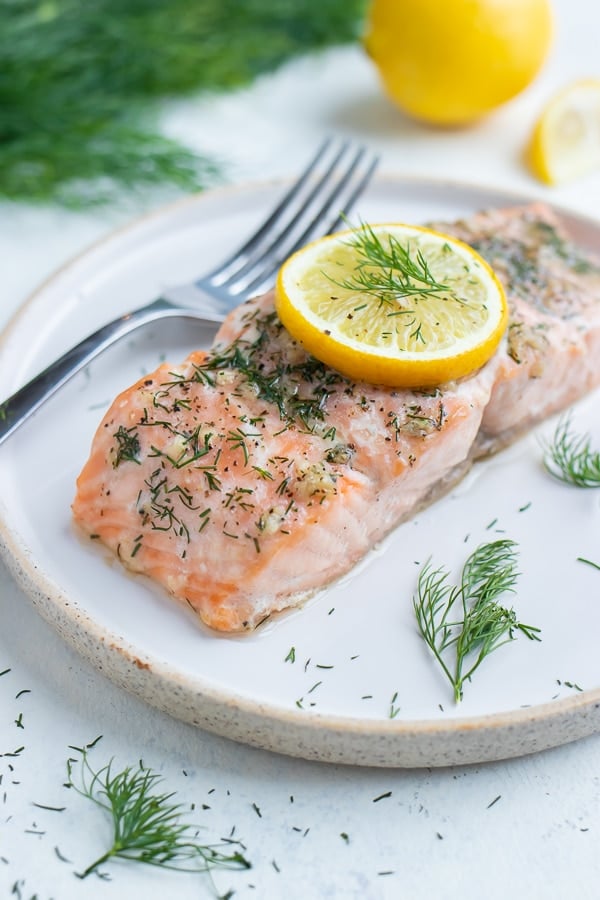 Lemon and dill salmon is served on a white plate with a fork.