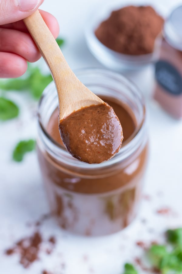 A big scoop of mole sauce is served from a jar.