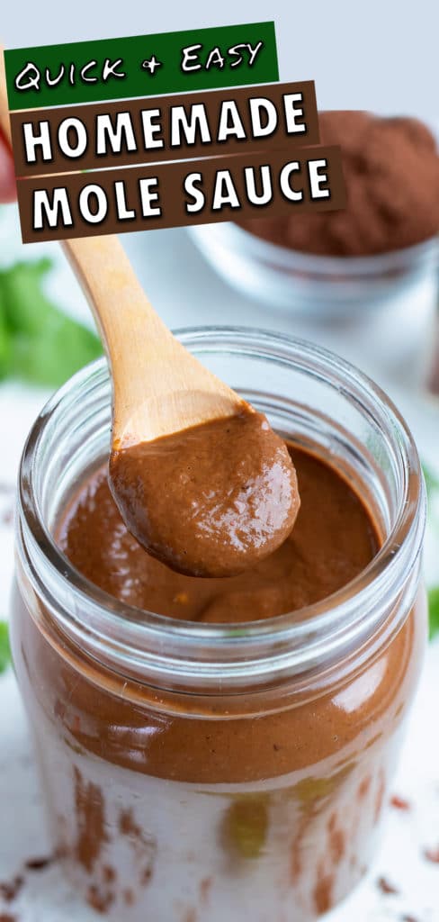 Authentic mole sauce is lifted up by a spoon from a jar.