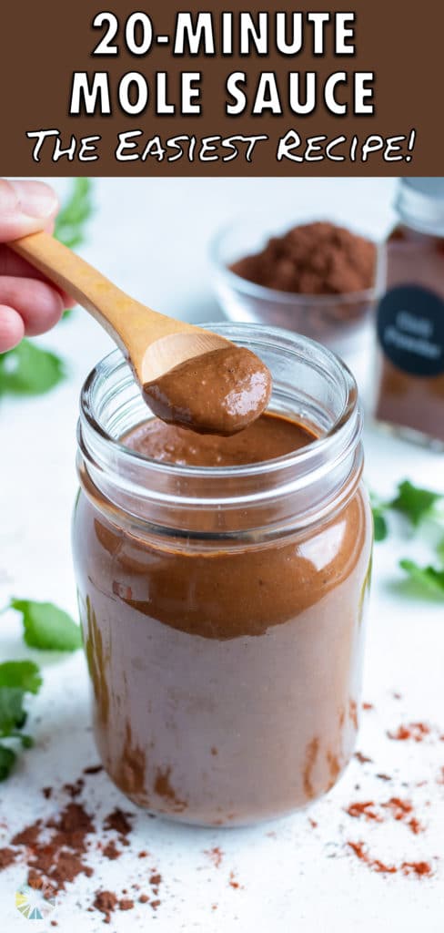 Mole sauce is lifted out of a jar with a metal spoon.