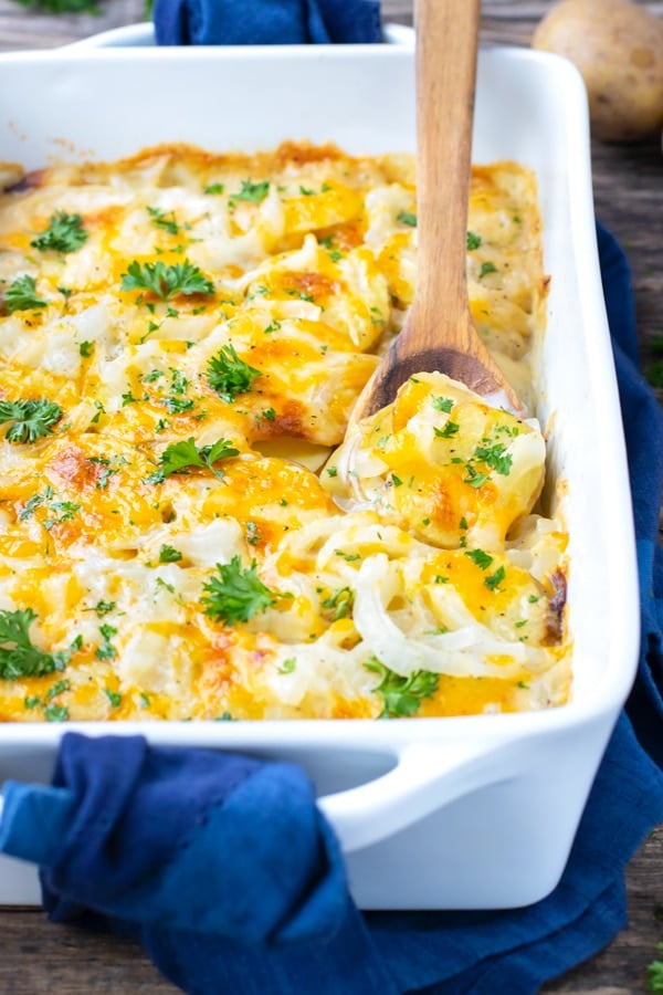 Homemade scalloped potatoes recipe with cheddar cheese and parsley sprinkled on top.