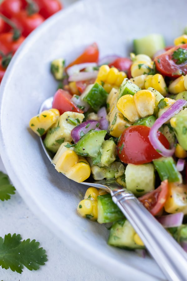 Avocado corn salad is served from a bowl for a light and refreshing side.