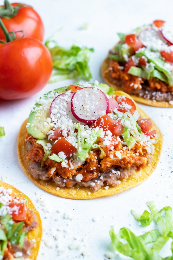 Easy chicken tinga tostadas are shown on the counter. 