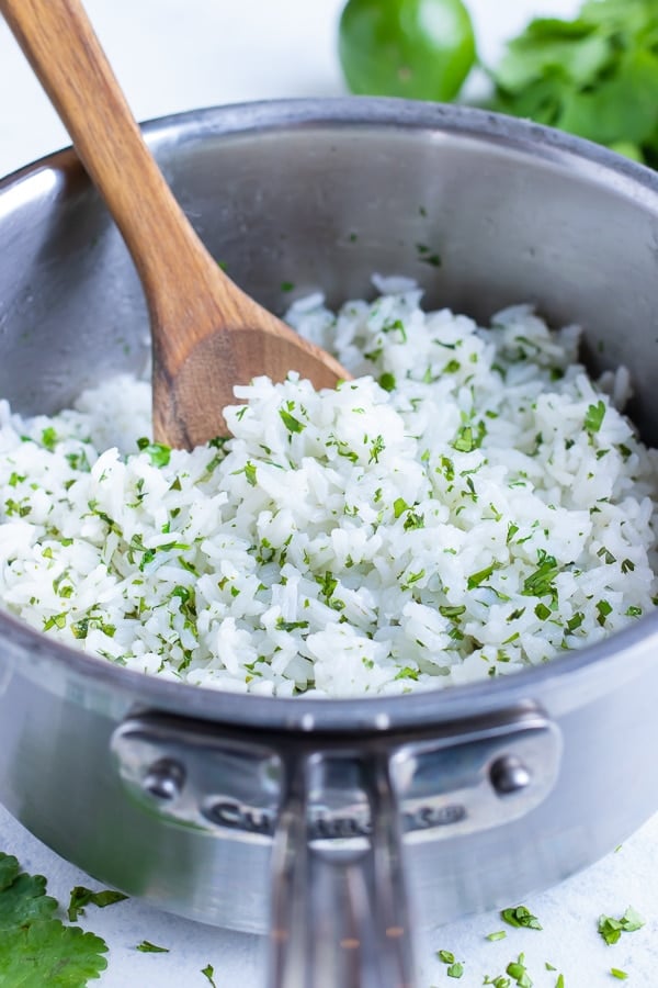 Cilantro lime rice is served with a wooden spoon for dinner.