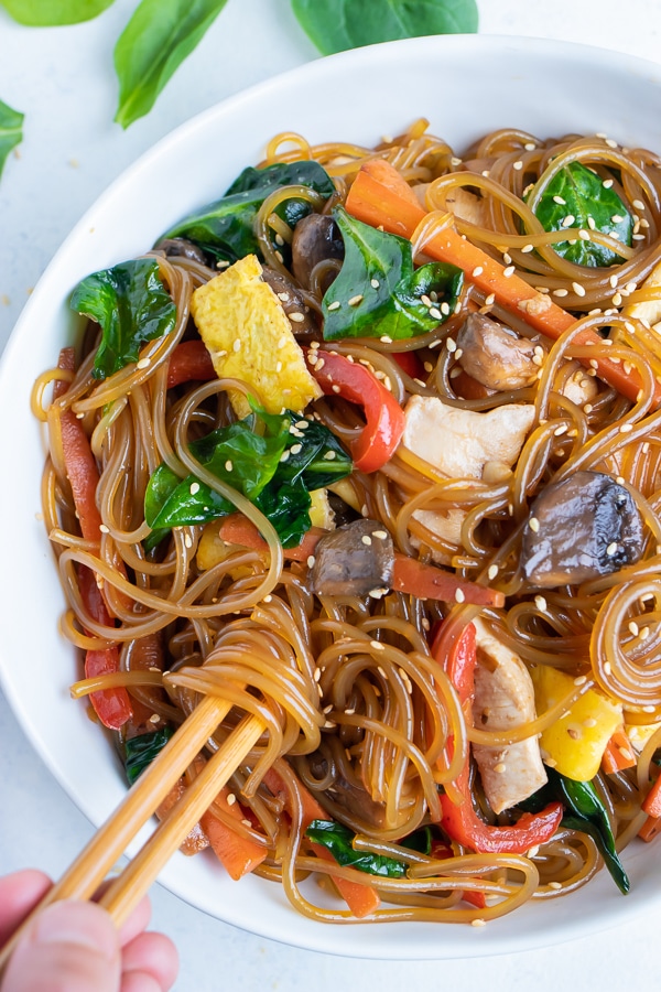 Easy Japchae recipe is eaten with chopsticks from a big white bowl.