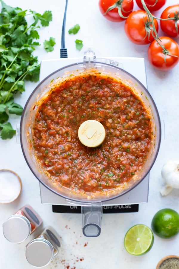 Salsa ingredients are pulsed in a food processor.