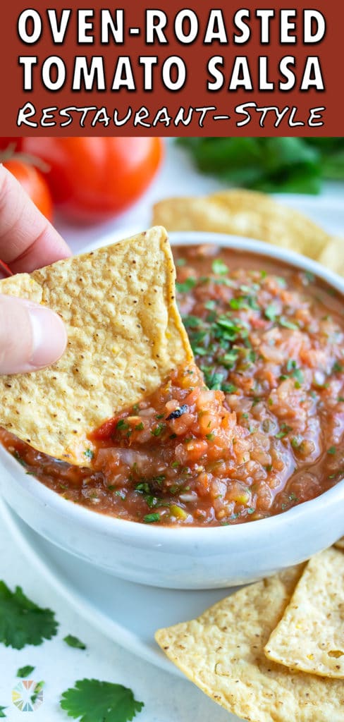 A tortilla chip is dipped into the bowl of roasted tomato salsa.