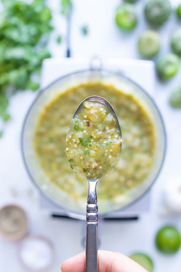 A spoon is used to lift up the salsa verde from the food processor.