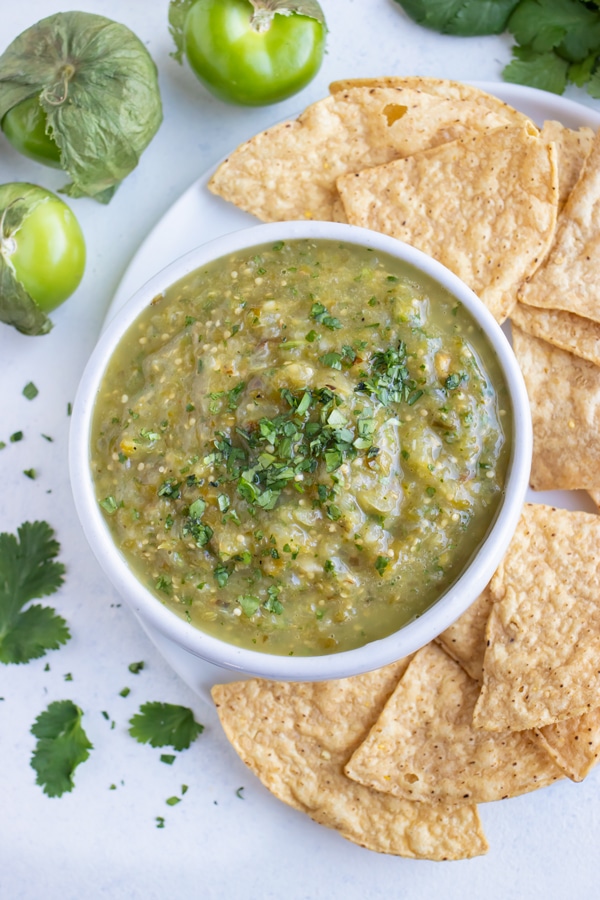 Salsa verde is served beside tortilla chips for a Mexican appetizer.