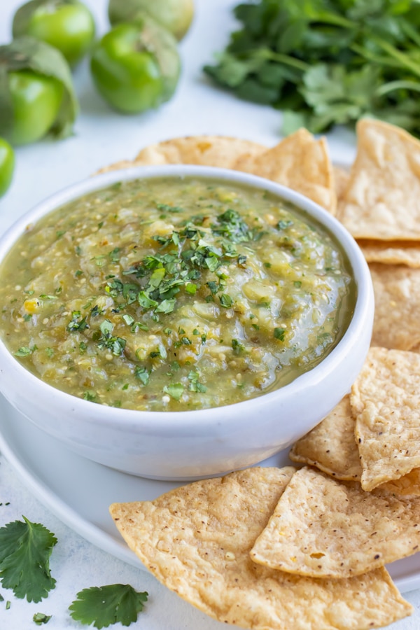 A bowl of healthy salsa verde is served with chips for an appetizer.