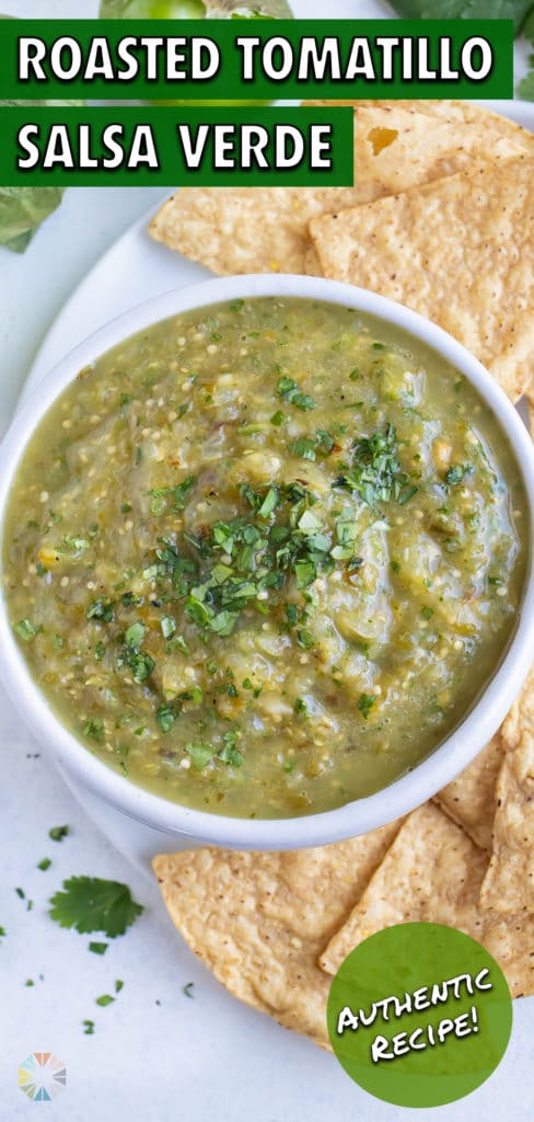 A bowl of tomatillo salsa verde is placed beside tortilla chips.