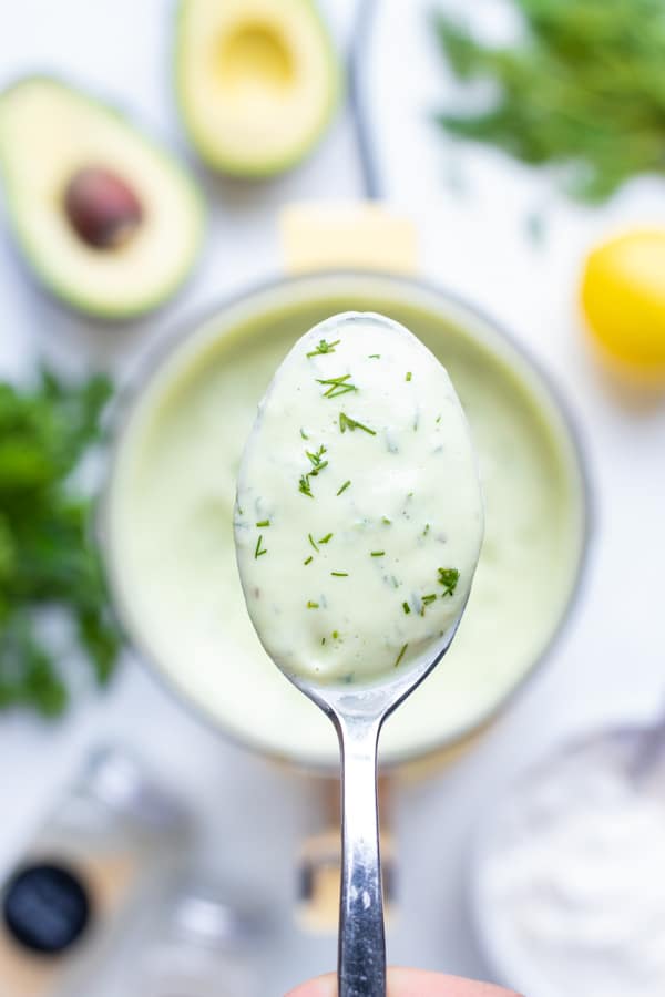 A spoon is used to lift up the healthy Avocado Ranch Dressing!