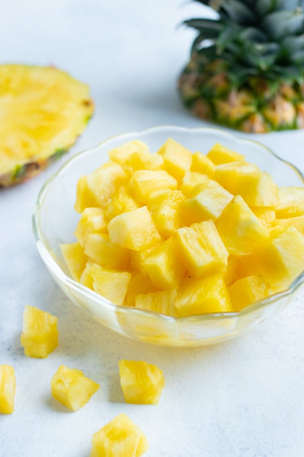 A bowl of pineapple cubes are set on the counter.