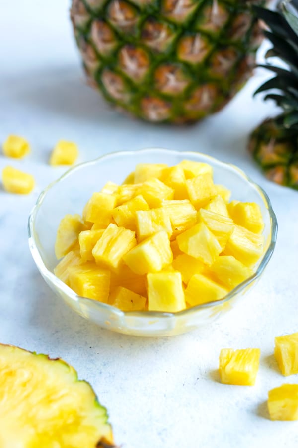 A bowl of pineapple cubes is shown on the counter.