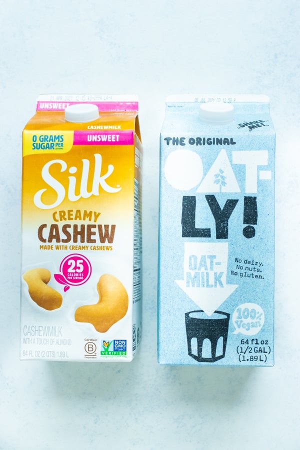 Cashew and oat milk are pictured as ingredients for a fruit smoothie.
