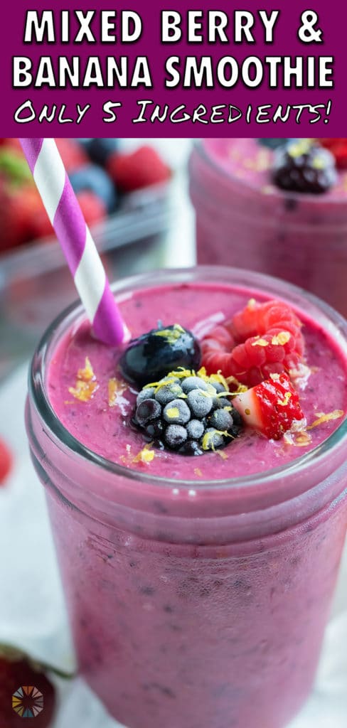 A berry smoothie is topped with frozen berries and fresh lemon zest.