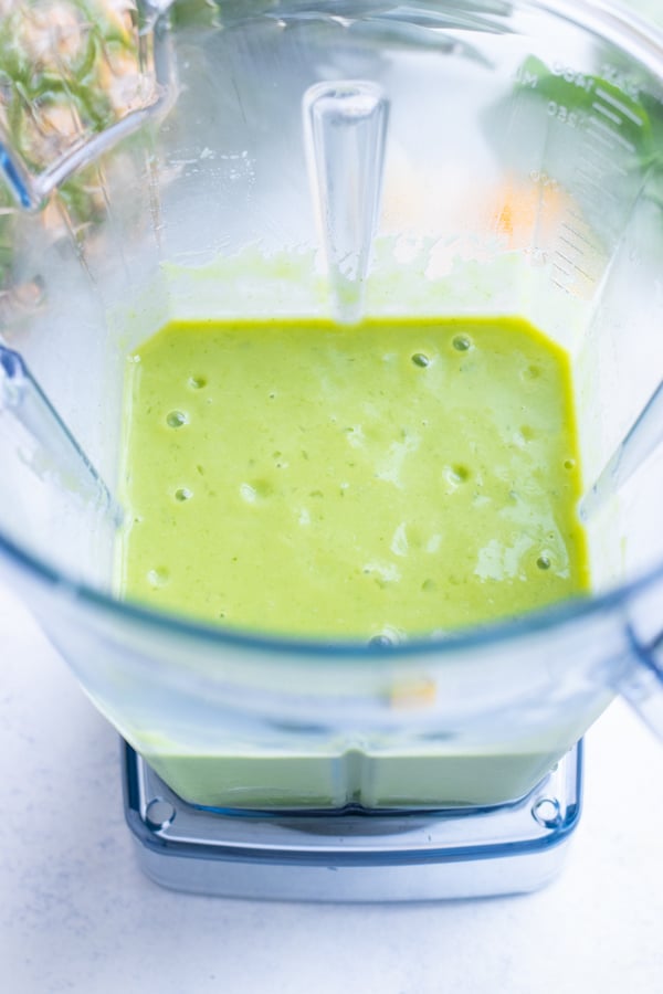 Tropical green smoothie is made in a vitamix or nutribullet.