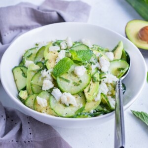 The Cucumber Crab Salad is served in a white bowl with a metal spoon.