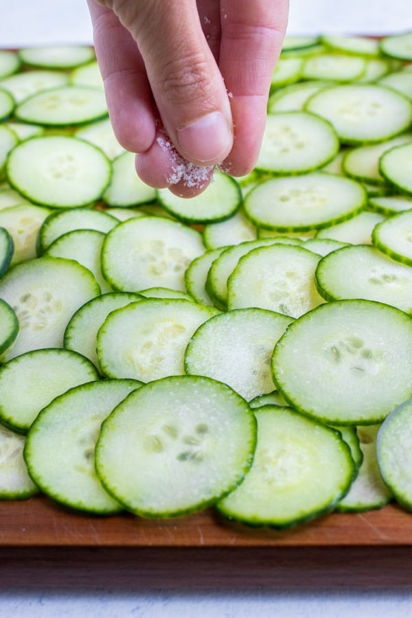 The thinly sliced cucumbers are salted and laid flat.