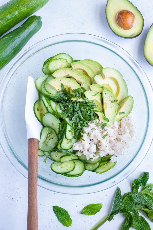 A bowl is filled with the cucumber crab salad ingredients.