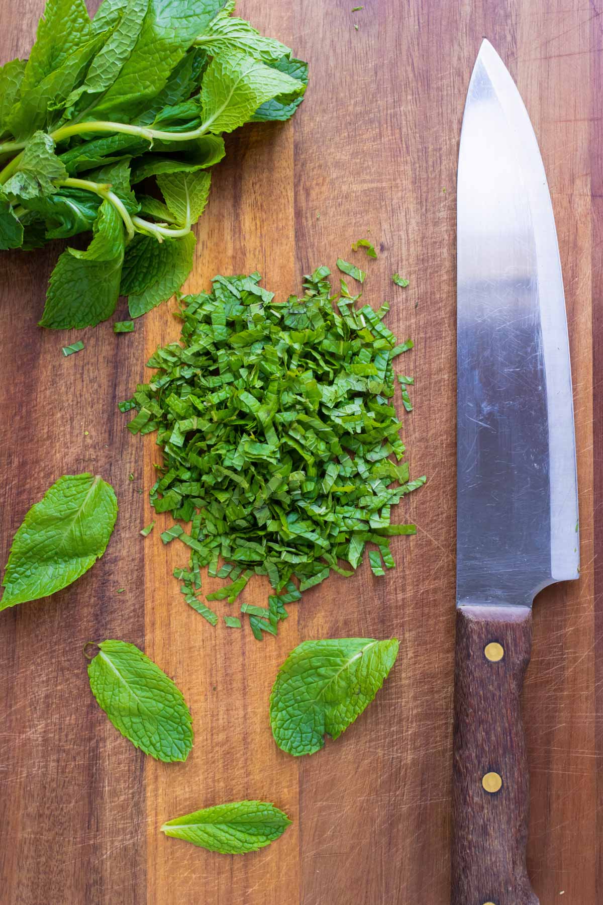 A cutting board with lime zest and a microplane and a citrus zester with fresh lime juice.