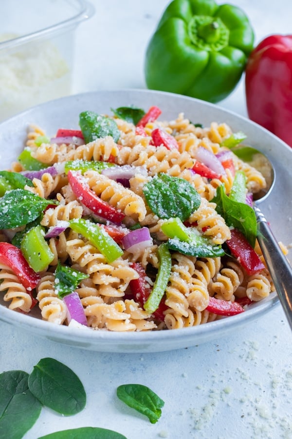 A bowl of Italian Pasta Salad is served with a spoon for a picnic side dish.