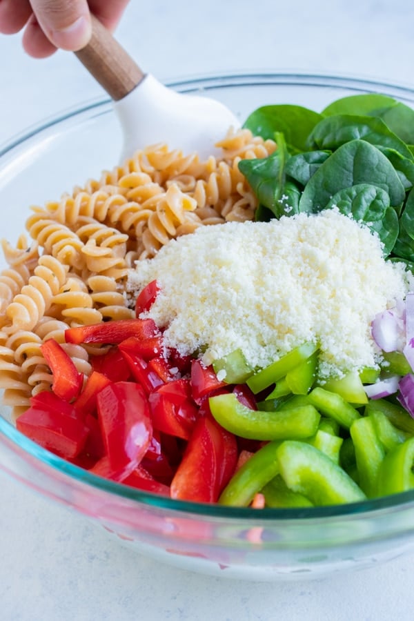 Chopped veggies, spinach, and Parmesan cheese are added to the bowl of noodles.