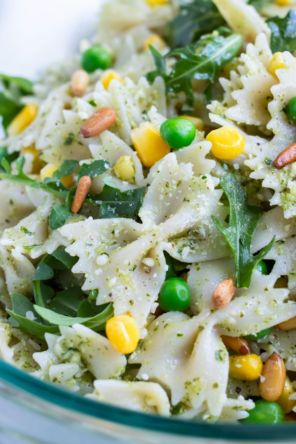 A close up pictures show all the ingredients in Pesto pasta salad.