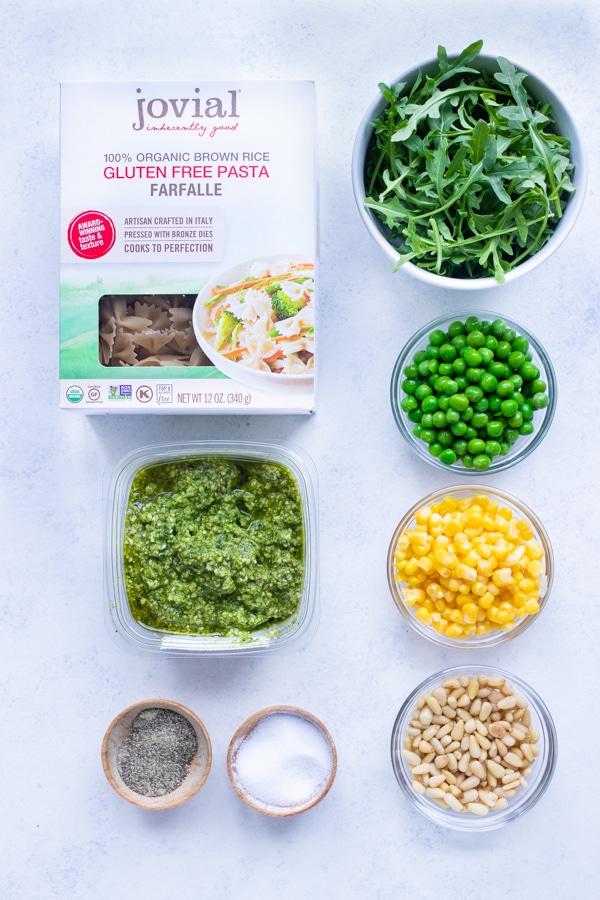 Arugula, pesto, pasta, peas, pine nuts, corn, salt, and pepper are the ingredients for this recipe.