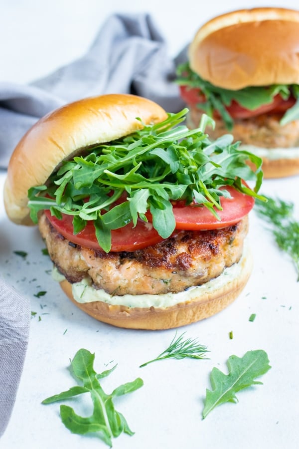 The top bun of the salmon burger is tilted off the salmon burger.