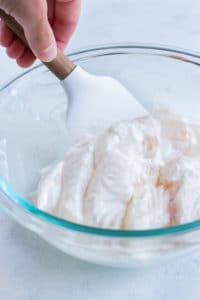 The fish fillets are covered in mayonnaise in a bowl.