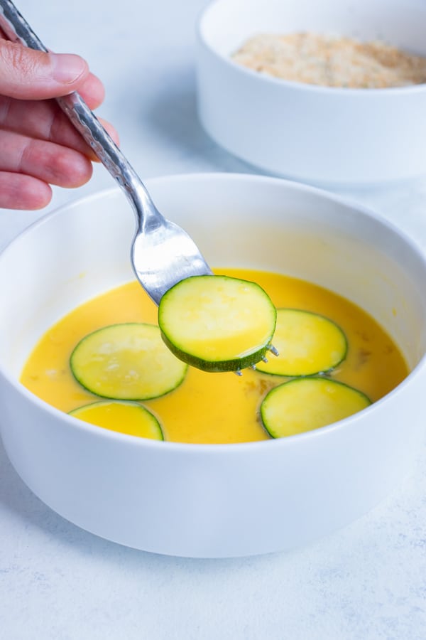 Zucchini chips are dipped in an egg mixture before being coated in breadcrumbs.