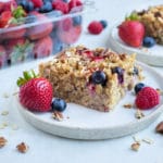 A serving of berry oatmeal is served on a white plate with fresh berries.