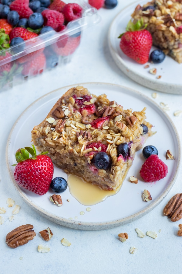 Baked oatmeal with berries is drizzled with syrup.