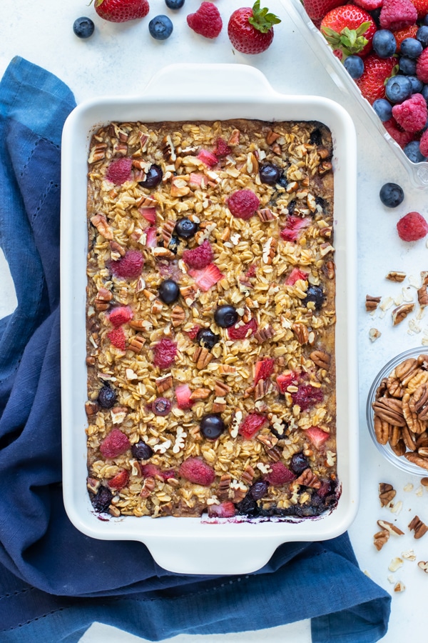 A dish of baked oatmeal is set on the counter near fresh berries.