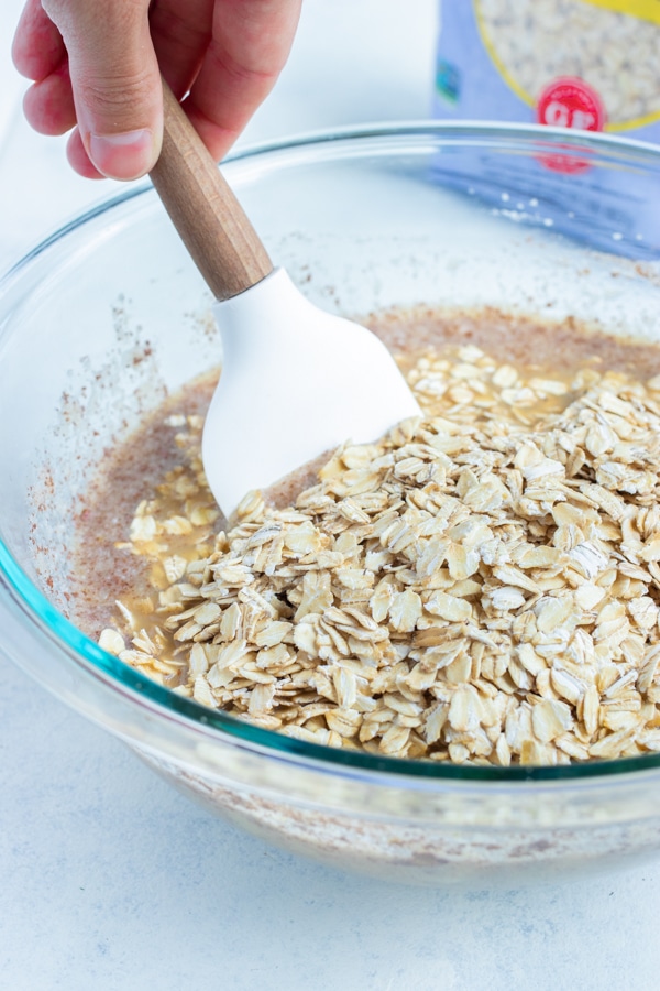 The oats are mixed into the mixture in a bowl.