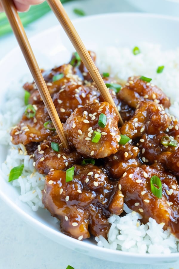 General Tsos Chicken is eaten with chopsticks and white rice.