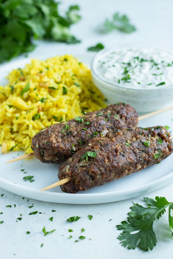 Two Lamb Kofta Kebabs are served with yellow rice.