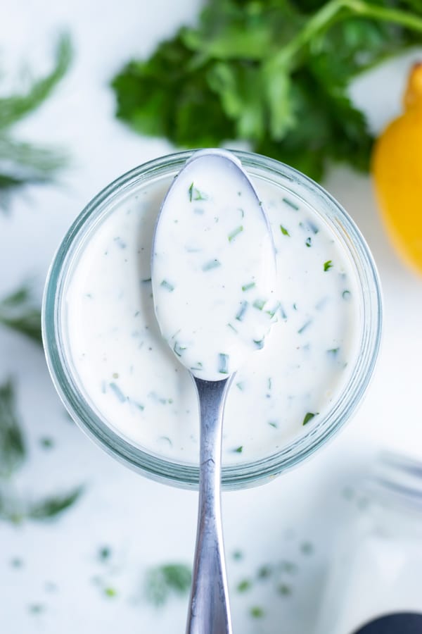 Ranch dressing is served with a metal spoon.