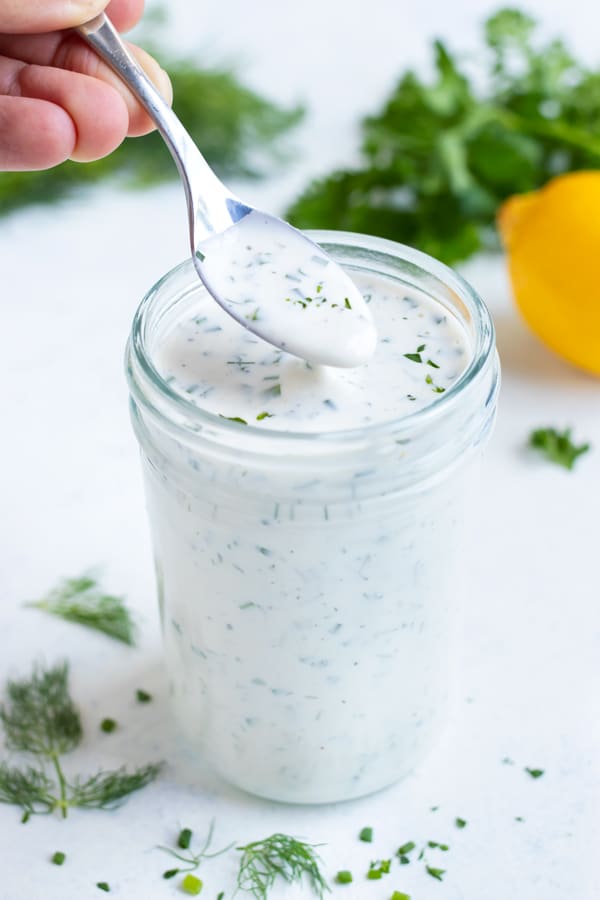 This homemade dressing with fresh herbs is on the counter for a healthy dip or sauce.